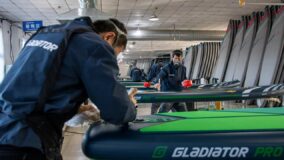 Worker bending over a GLADIATOR PRO SUP board