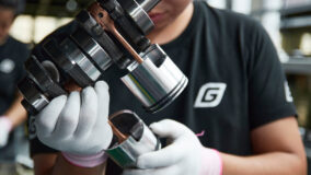 Worker holding an engine piston and connecting rod